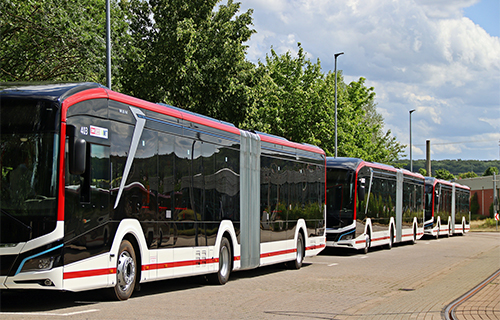 Seitenaufnahme von drei Elektrobussen auf dem Betriebshof.